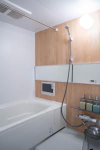 a bathroom with a bathtub and a microwave on the wall at Zabo Hills 303 in Sapporo