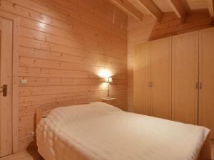 a bedroom with a white bed in a wooden wall at Chalet in a peaceful location near Nijlen in Nijlen