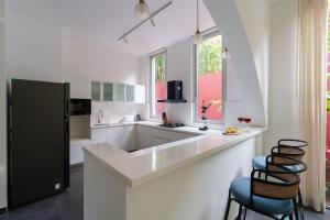 a white kitchen with a counter and stools at La Verona by The Blue Kite - 2 & 3 BHK Villas in Assagao with Private Pool, Garden, Caretaker, Kitchen & Security in Assagao +191 photos