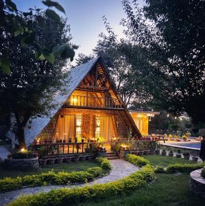 a house with a thatched roof in a garden at The Cabin Dharamshala in Dharmsala