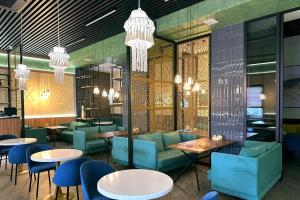 a restaurant with blue chairs and tables and chandeliers at Hotel Bereket Karaganda in Karagandy