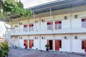 a white building with red doors and a balcony at RedDoorz Syariah at Djaya Guest House Padang in Padang