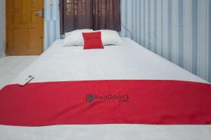 a bed with a red blanket on top of it at RedDoorz at Kuning GH Jatinangor in Sayang