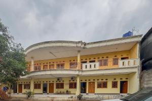 a large yellow building with a balcony on it at RedDoorz at Kuning GH Jatinangor in Sayang