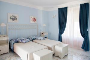 two beds in a bedroom with blue walls and curtains at Hotel Residence Mendolita in Lipari +82 photos