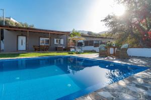 a swimming pool in front of a house at Villa Rose by PosarelliVillas in Georgioupolis