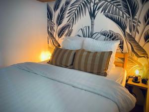 a bedroom with a bed with a tropical wallpaper at Studio premium, à 50m du Lac d'Ardres avec terrasse in Ardres