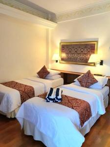 a hotel room with three beds with white sheets at C&C Jayakarta Apartment Legian Bali A in Seminyak