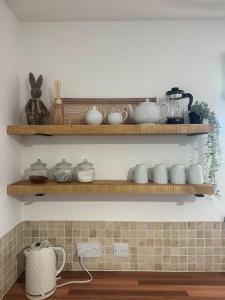 a kitchen with wooden shelves with dishes on it at Parr Cottage at Snape Castle Mews in Bedale +18 photos