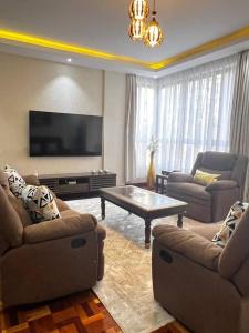 a living room with two couches and a flat screen tv at Charming luxury condo with pool in Kileleshwa in Nairobi