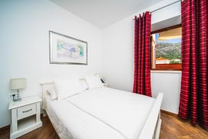 a bedroom with a bed and a window with red curtains at Apartments Vila Riva in Slano +48 photos