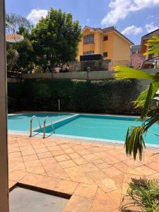 a blue swimming pool with a building in the background at Charming luxury condo with pool in Kileleshwa in Nairobi