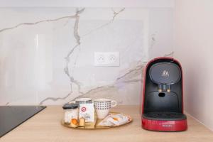 a coffee maker and two cups on a table at Baignoire balnéo avec climatisation in Saint-Étienne