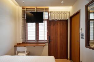 a bedroom with a bed and a television and a window at ROOMS at Number60 Khaosan Bangkok in Bangkok