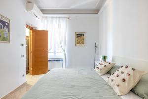 a white bedroom with a large bed with two pillows at Maurice's Apt, hidden gem in Rome for food lovers in Rome