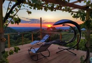 two chairs and an umbrella on a deck with the sunset at Vineyard Cottage Sončni grič in Trebnje