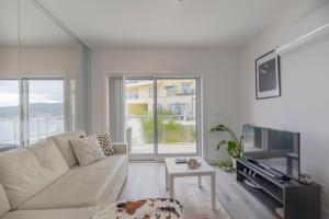 a living room with a white couch and a tv at Cliffs Apartment - Astonishing view over Sesimbra bay by Trip2Portugal in Sesimbra