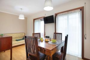a dining room with a table and chairs and a couch at Espinho Retreat with Balcony in Espinho