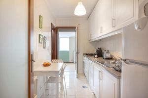 a kitchen with white cabinets and a table with oranges on it at Espinho Retreat with Balcony in Espinho