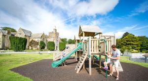 a man and a child playing on a playground at Trelawne Manor Holiday Park in Looe