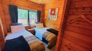 a room with two beds in a log cabin at Hanmer's Coziest in Hanmer Springs