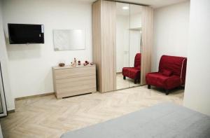 een slaapkamer met 2 rode stoelen, een tv en een dressoir bij Home Maria in Napels