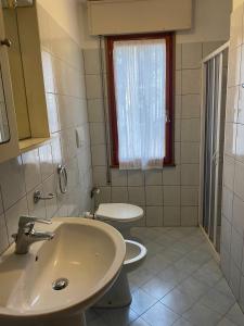 a bathroom with a sink and a toilet and a window at Comfy apartment in Rosolina in Rosolina Mare