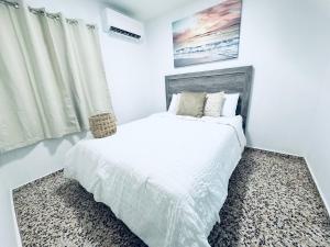 a white bedroom with a bed and a window at GD Vacation Rentals in Arecibo
