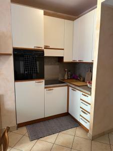 una cucina con mobili bianchi e un microonde nero di Appartamento Edera ad Aprica