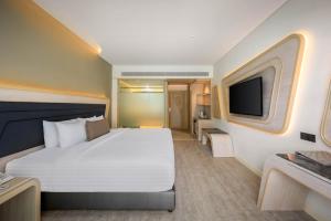 a hotel room with a bed and a flat screen tv at Amora Beach Resort Phuket in Bang Tao Beach