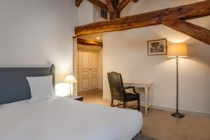 a bedroom with a bed and a desk with a lamp at Hostellerie de l'Écu de Bretagne in Beaugency +23 photos
