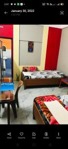 a room with two beds and a table and a mirror at Pulu Restaurant & lodge in Majuli