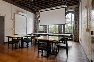 法兰克福The Delegate Hotel的一间会议室,配有桌椅和大屏幕