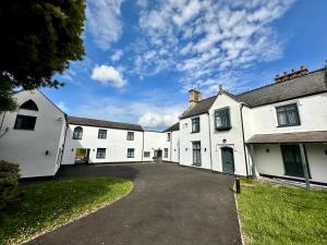 a group of white buildings with a driveway at Rhode Lane - Serviced Apartments Bridgwater in Bridgwater