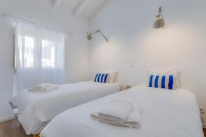2 letti bianchi in una camera bianca con finestra di Casa Maria Rota ad Aljezur
