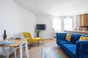 a living room with a blue couch and a table at Stylish Flat with Stunning Sea Views Ilfracombe in Ilfracombe