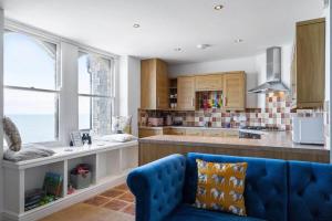 a kitchen with a blue couch in a room at Stylish Flat with Stunning Sea Views Ilfracombe in Ilfracombe