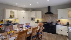 a kitchen with white cabinets and a table with chairs at Magnificent house on the West Coast of Ireland in Mullagh