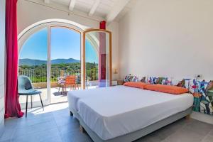 a bedroom with a large bed and a balcony at Baia di Spartaia 1 in Procchio