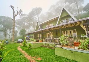a green house with a car parked in front of it at The Yela Munnar by VOYE HOMES , Nestled in Cardamom Plantation in Munnar