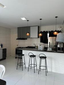 eine Küche mit drei Barhockern und einer Theke in der Unterkunft ParkMar III - São José, Maragogi in São José da Coroa Grande
