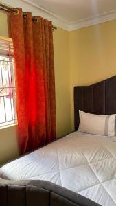 a bedroom with a bed and a window with curtains at Spacious City Home in Kampala