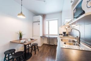 a kitchen with a sink and a table with stools at Forenom Serviced Apartments Helsinki Lapinlahdenkatu in Helsinki