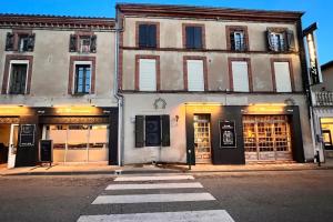 a building on a street with a crosswalk in front at Cocon Coeur de Ville in Villefranche-de-Lauragais