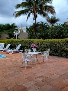 a patio with a table and chairs and palm trees at Flat confortável in Brasilia