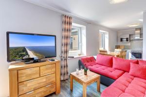 a living room with a red couch and a flat screen tv at Peenemünde, Seglerhafen_SB_Jolle 17 in Peenemünde +9 photos