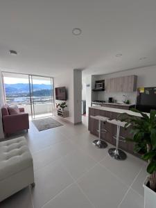 a white living room with a couch and a kitchen at Hermoso apto en poblado con piscina in Medellín