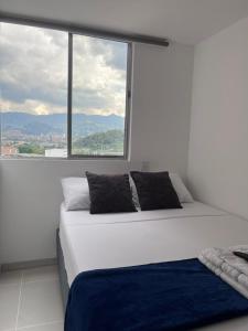 a white bed with a large window in a room at Hermoso apto en poblado con piscina in Medellín