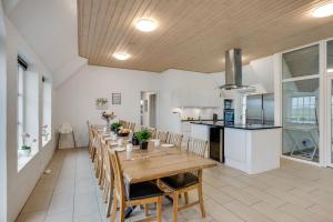 a kitchen and dining room with a long table and chairs at Large Holiday Home For 20 People With Large Pool, Hot Tub For 7 People And Activity Room in Ringkøbing