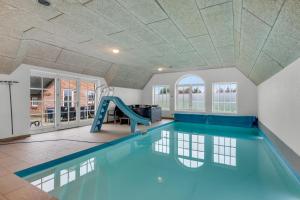 an indoor swimming pool with a slide in a house at Large Holiday Home For 20 People With Large Pool, Hot Tub For 7 People And Activity Room in Ringkøbing